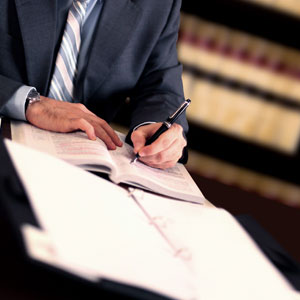A man in a suit writing on a legal document - Donald Janklow Attorney at Law